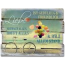 Holzschild mit Fahrrad und Luftballons vor dem Strand und...